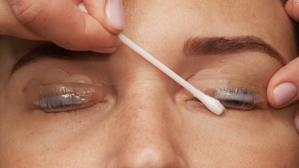 Master applies special glue before the eyelash curling procedure, close up.