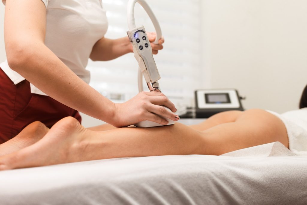 Woman doing vacuum anti-cellulite massage on her legs. Vacuum massage device